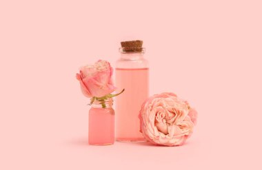 Pembe arka planda kozmetik yağı ve güller