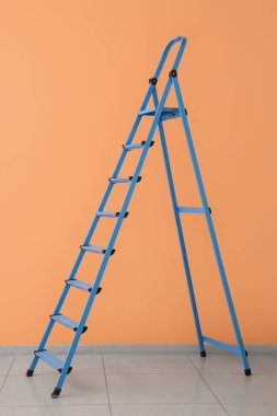 Mavi merdiven turuncu duvarın yanında.
