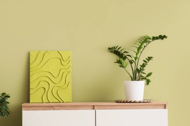 Yeşil duvarın yanındaki klozette boyalı bitki.