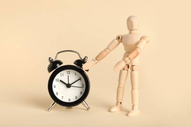 Bej arka planda çalar saati olan ahşap manken.