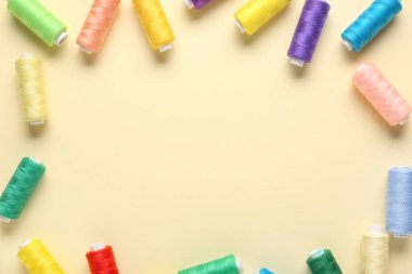 Bej arkaplanda renkli iplik makaralarından yapılmış çerçeve