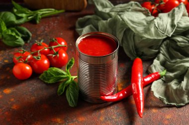 Fesleğen yapraklı teneke domates ezmesi ve koyu arkaplanda kırmızı biber, yakın plan.