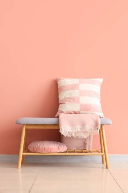 Yastıklı gri bank ve pembe duvarın yanında battaniye