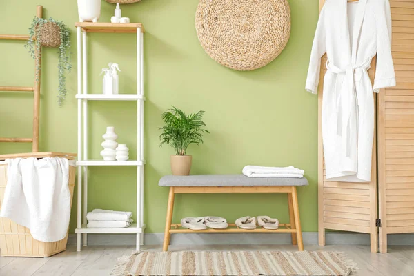 Rafları, terlikleri ve gri bankları olan şık bir banyo.