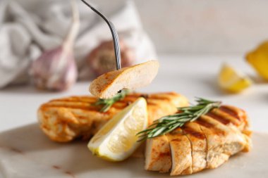 Açık arkaplanda biberiye ve limon dilimli kesilmiş tavuk göğsü yemek.