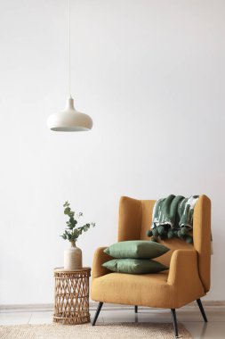 Koltuk, ekoseli yastıklar ve okaliptüs dalları odadaki sehpanın üstündeki vazoda.