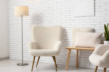 Işık odasında lamba, bank ve yastıklı beyaz koltuklar.