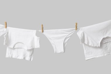 Temiz giysiler gri arka planda çamaşır ipine asılı.