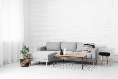 Interior of light living room with window, grey sofa and table