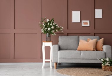 Rahat bir kanepe, masa ve çiçek açan yasemin çiçekleri oturma odasının içinde.