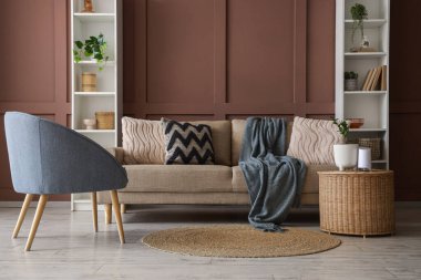 Oturma odasının içinde rahat bir kanepe, raf üniteleri ve kahverengi duvarın yanındaki masa.