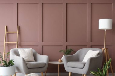 Şık oturma odasının içinde lamba, koltuk ve bitkiler var.