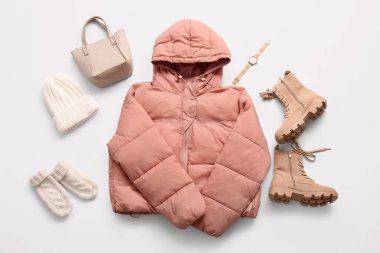 Çizmeleri, kol saati ve beyaz arka planda izole edilmiş kış aksesuarları olan şık kısa pembe kabarık ceketli.