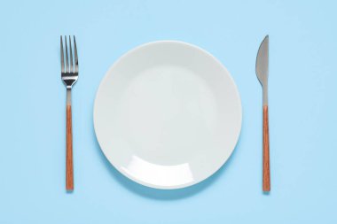 Gümüş çatallı tabak ve mavi arka planda bıçak.