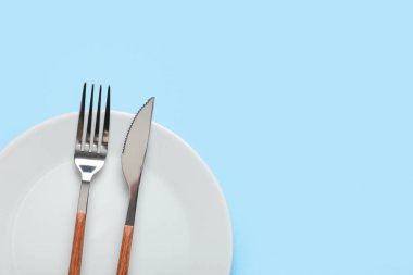 Gümüş çatallı tabak ve mavi arka planda bıçak.