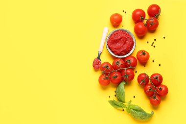 Bir kase lezzetli domates ezmesi biberli ve sarı arka planda fesleğen yapraklı.