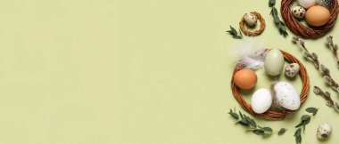 Wreaths, Easter eggs, pussy willow branches and feathers on green background with space for text
