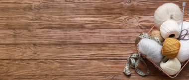 Örgü ipliği, mezura, makas ve iğnelerle dolu sepet ahşap arka planda metin için yer var