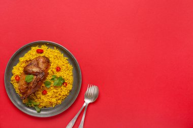 Kırmızı arka planda geleneksel tavuk biryani tabağı