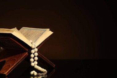 Kuran ve siyah arkaplanlı Müslüman boncuklu Rehal. Ramazan kutlaması