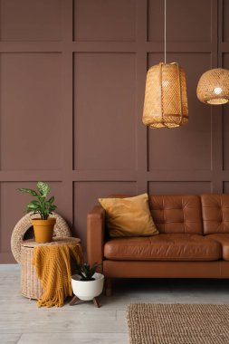 Rahat kahverengi kanepesi, çiçekleri ve hasır lambaları olan şık bir oturma odası.