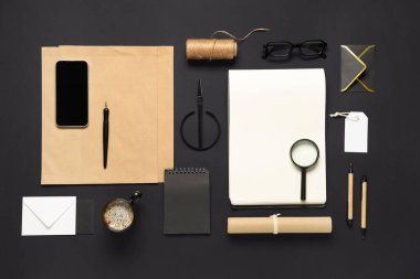 Cep telefonu, kahve fincanı, makas ve siyah arka planda teslimat kağıdı içeren kompozisyon