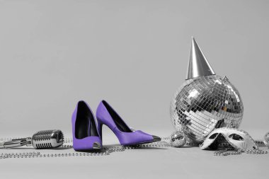 Yüksek topuklu, disko topları ve gri arka planda parti dekoru.