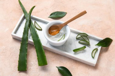 Bir kase aloe vera jeli ve bej arkaplanda yapraklar