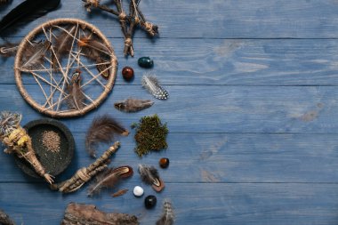 Mavi ahşap arka planda tüyleri olan şaman aksesuarları.