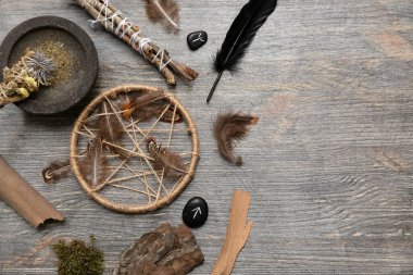 Koyu ahşap arka planda tüyleri ve ağaç dalları olan şaman aksesuarları.