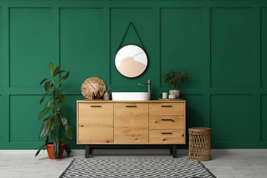 Küvet, banyo aksesuarları ve banyo içlerindeki yeşil duvarın yanındaki bitkiler.