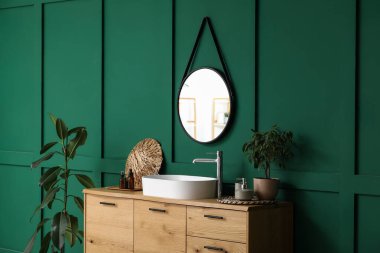 Küvet, banyo aksesuarları ve banyo içlerindeki yeşil duvarın yanındaki bitkiler.