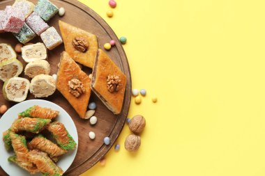 Geleneksel baklava, Türk lezzeti ve sarı arkaplanda renkli şekerler olan bir pano. Nowruz Bayram kutlaması