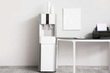 Modern su soğutucusu ve çalışma odası beyaz duvarın yanında.