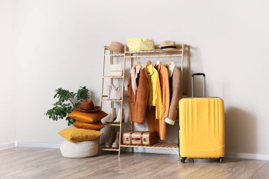 Giysilerle, çiçeklerle ve odanın iç tarafındaki bej duvarın yanındaki bavullarla dolu.