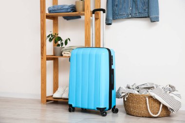 İçinde bavul, raf ve giysiler olan bir oda.