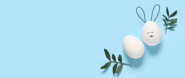 Komik Paskalya yumurtaları ve mavi arkaplandaki yapraklarla metin için alanı olan kompozisyon