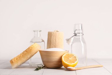 Bir kase kabartma tozu, sirke, limon ve temizlik malzemelerini beyaz arka planda seramik masaya koyun.