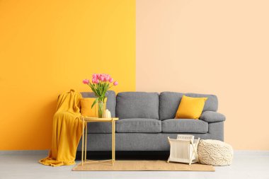 Gri kanepesi ve kahve masasında güzel lale çiçekleri olan şık bir oturma odası.