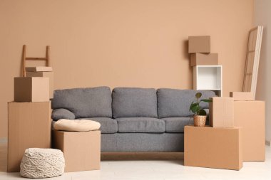 Gri kanepe, raf ünitesi ve bej duvarın yanında bir sürü paket olan oturma odasının içinde.