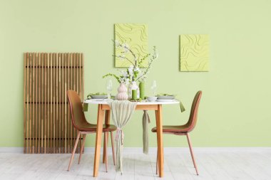 Tabakları, mumları ve çiçek açan ağaç dalları olan zarif bir masa.