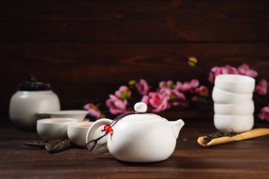 Teapot with brewed Asian tea on dark wooden background