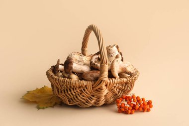 Wicker basket with fresh mushrooms on beige background