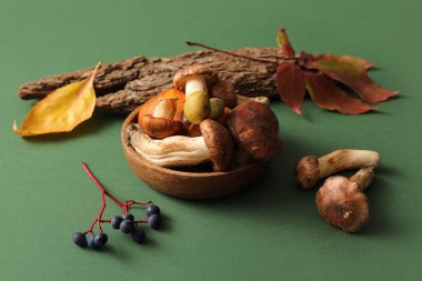 Bowl with fresh mushrooms on green background, closeup