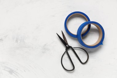 Açık arkaplanda makas ile mavi maskeleme bandı ruloları