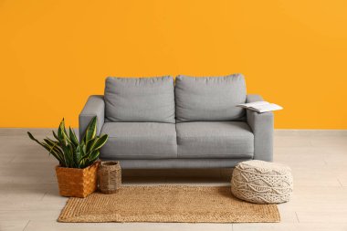 Rahat kanepe, puf ve çiçekli oturma odasının içinde.