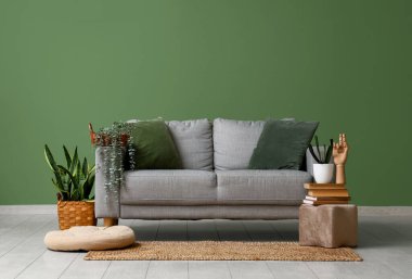 Rahat kanepesi, çiçekleri ve yeşil duvarı olan oturma odasının içinde.