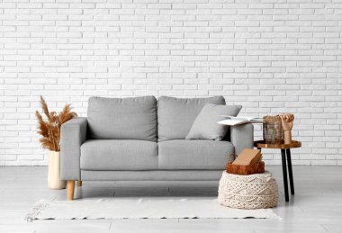 Interior of living room with grey comfortable sofa, pouf and vase with pampas grass