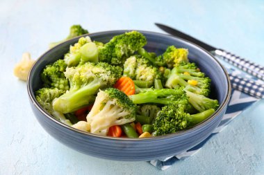 Bowl of stewed mixed vegetables on light blue background