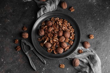 Gri arka planda lezzetli ceviz ve fındık kıracağı olan tabak.